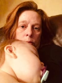 Tracey holds her sleeping baby daughter 